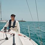 A yachtsman controls a sailing yacht on the open sea, demonstrating skills in maritime navigation